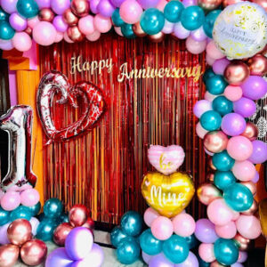 Romantic anniversary decoration setup with heart balloons, fairy lights, and rose petals