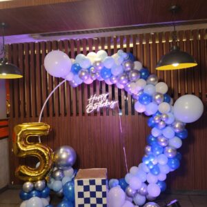 Birthday balloon decoration setup with LED lights and themed backdrop