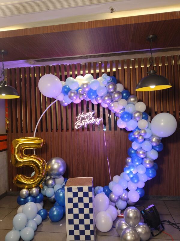 Birthday balloon decoration setup with LED lights and themed backdrop
