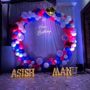 Romantic ring-shaped birthday balloon decoration with red, pink, blue, and white balloons, heart foil balloons, 'Happy Birthday' neon sign, and custom LED name lights – Vruddhi Events Hyderabad