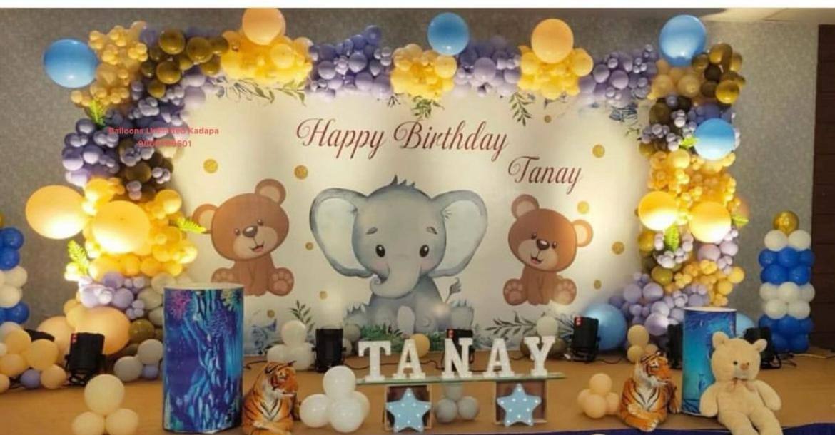 Helium balloon decoration Hyderabad for jungle theme birthday party with pastel balloons, elephant backdrop, and custom name display by Vruddhi Events.