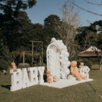 Charming outdoor baby event setup with teddy bears and balloons.