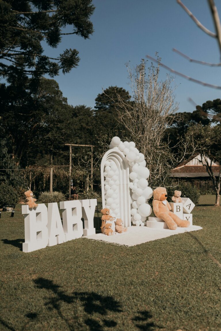 Charming outdoor baby event setup with teddy bears and balloons.