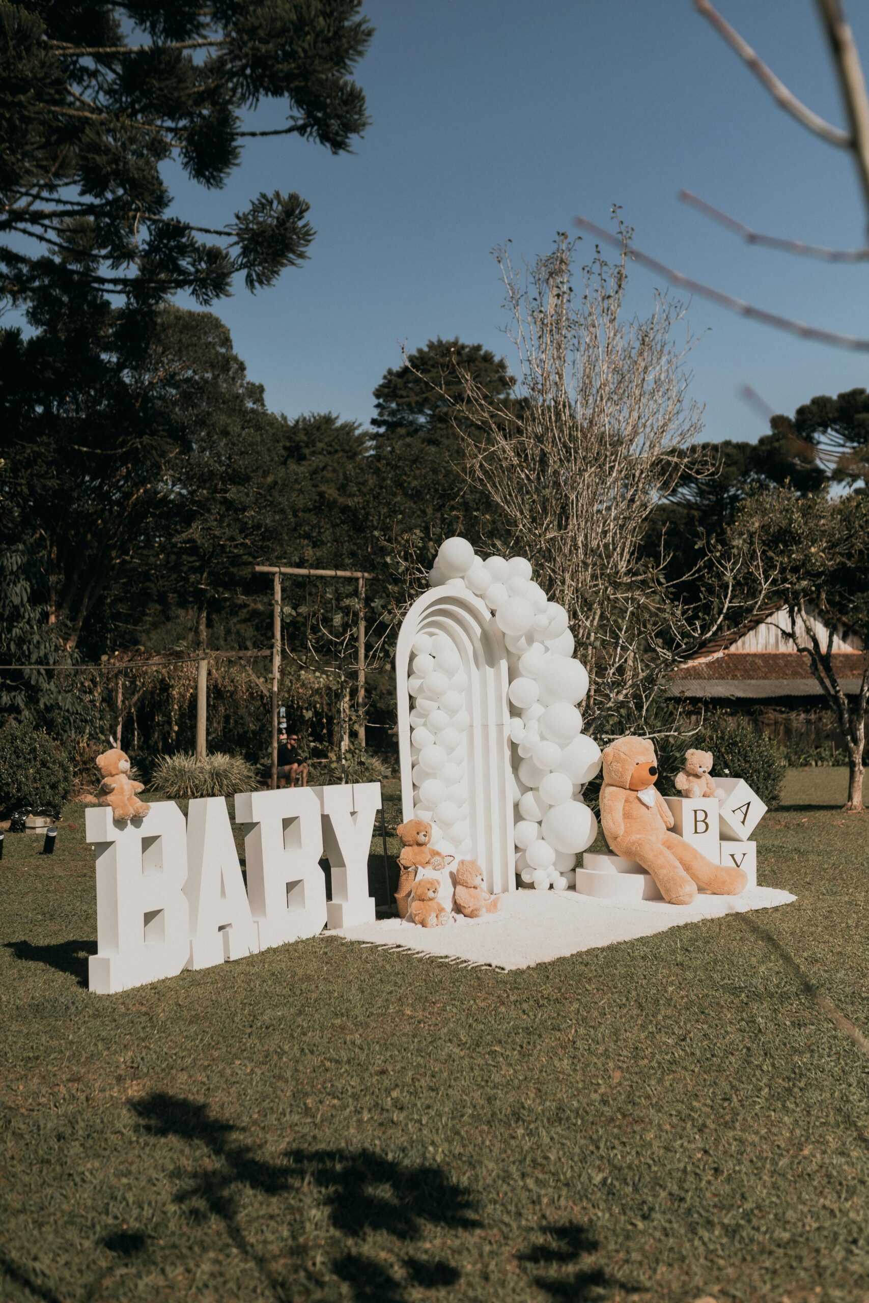 Charming outdoor baby event setup with teddy bears and balloons.