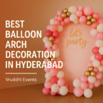 Colorful balloon arch decoration with pink, white, and gold balloons arranged in an elegant style, featuring 'let's party' text, promoting Vruddhi Events as the best balloon arch decorators in Hyderabad.